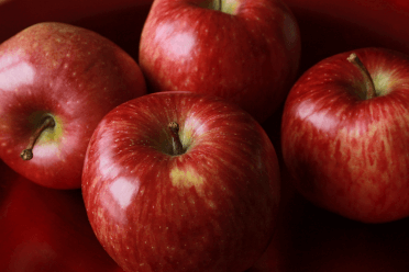 Four shiny red apples.