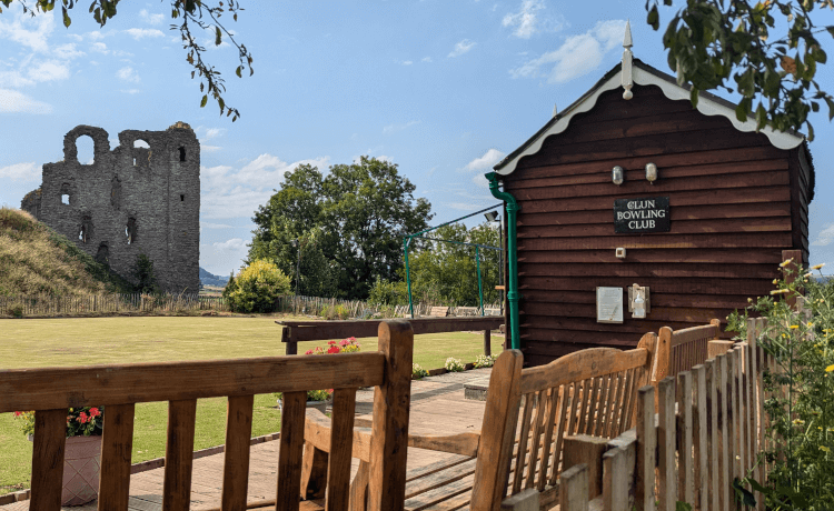 The ruin of Clun Castle stands in the background, with a neatly kept bowling green in front, complete with wood-panelled clubhouse.