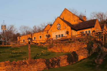 Low winter sunlight illuminates a pretty stone pub in the Cotswolds.