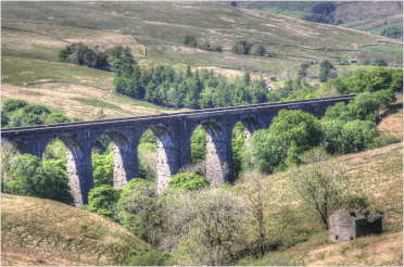 A large stone multi-arched viaduct carries the trainline over Dentdale.