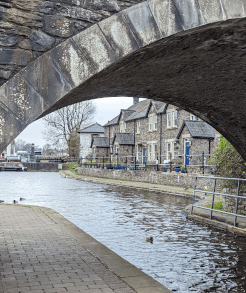 A view under a stone bridge of stone houses lining the Brecon Basin, the end of the canal and the Usk Valley Walk.