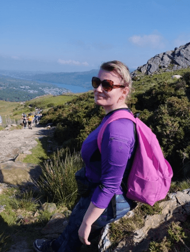 Gosia pauses to let other walker past as she makes her way up the Llanberis Path, with the town of Llanberis visible in the distance.