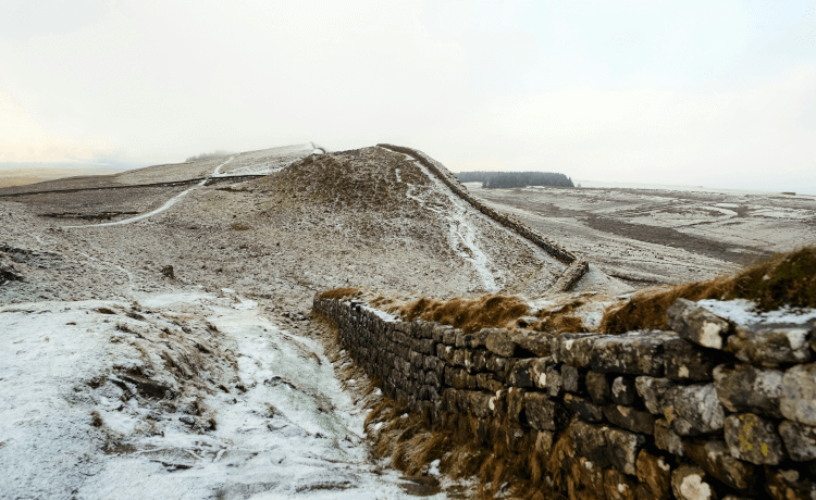 Hadrian's wall zig-zags through the hilly terrain of Northumberland, dusted with light snow in winter.