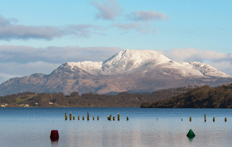 Snowy peaks stand above the blue waters of Loch Lomond, one of our favourite winter wonderlands for UK walks.