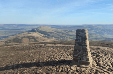 The trig point at the top of Mam Tor. A tapering stone structure with a flat top.