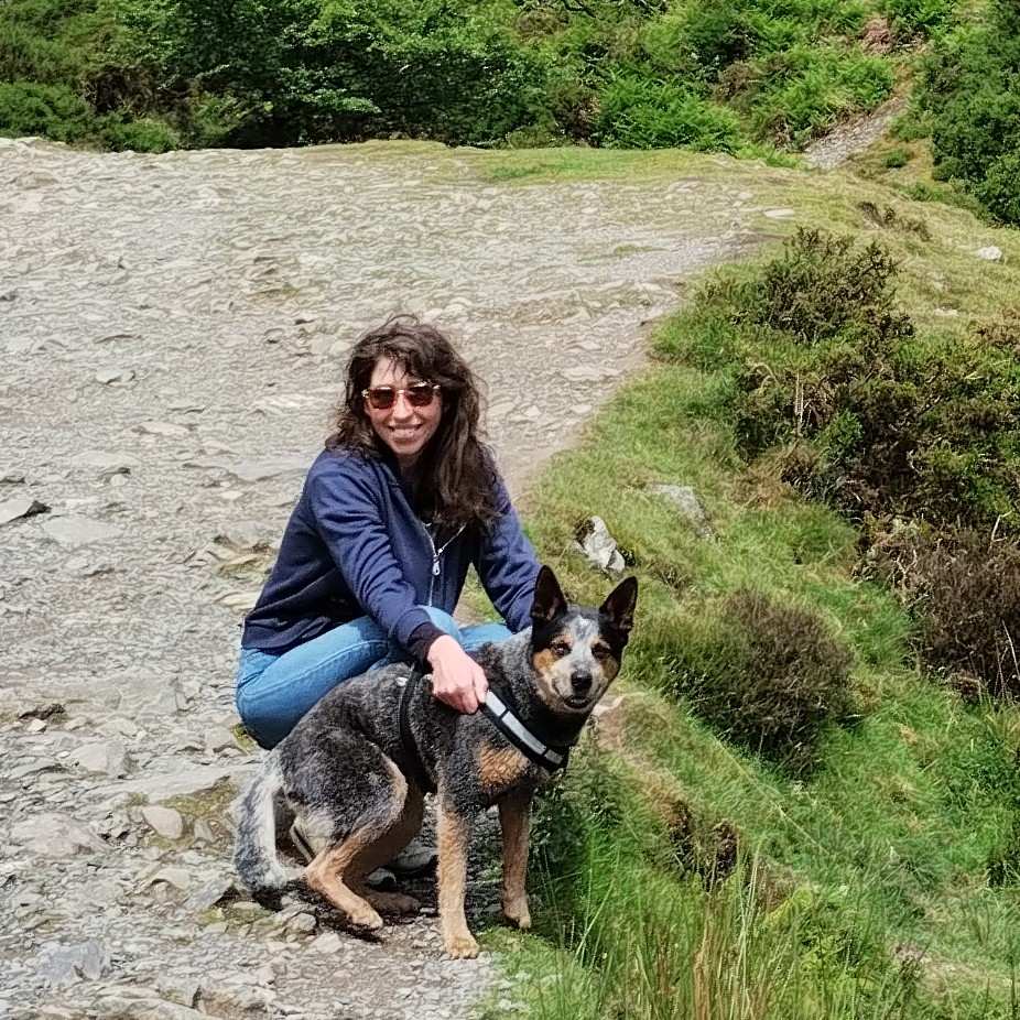 Monika, tour pack administrator at Contours Holidays, sits with her dog Jesse out in the English countryside on a hot summer day.