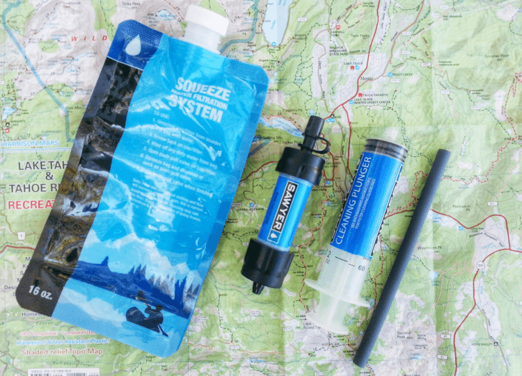 A Saywer squeeze pouch and mini filter arranged on top of a walking map.