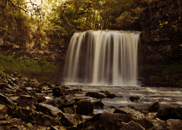 Water rushes over the stone in a wide curtain at Sgwd Yr Eira in the Brecon Beacons. The waterfall grows more powerful in autumn, when the Welsh rain fills the rivers.