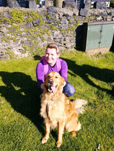 Gosia crouches beside a friendly golden retriever near the foot of Snowdon.