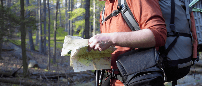 A man in full walking kit with a map on hand adopts the navigator persona.