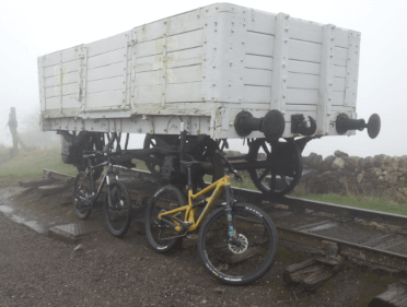 On a foggy winter day, a yellow mountain bike stands propped against one of the carriages from the retired railway that once occupied the Tissington Trail.