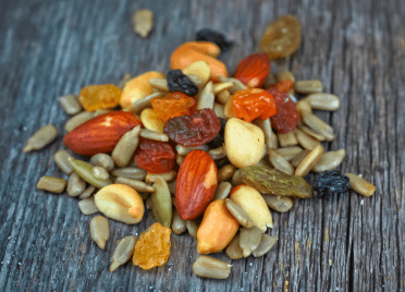 A handful of trailmix sits on a table. It's a mix of different nuts and seeds.