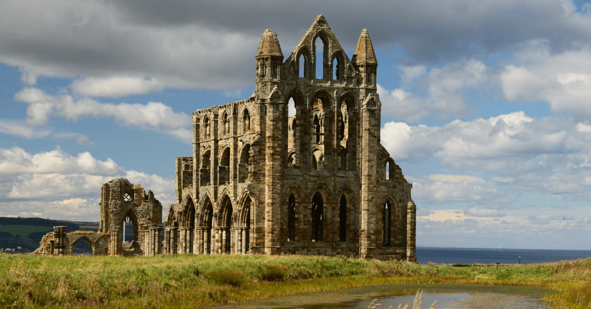 Whitby Abbey, a fairly complete ruin, stands on the headland over Whitby, with a pond in front and the sea behind. The site helped inspire Bram Stoker's Dracula.
