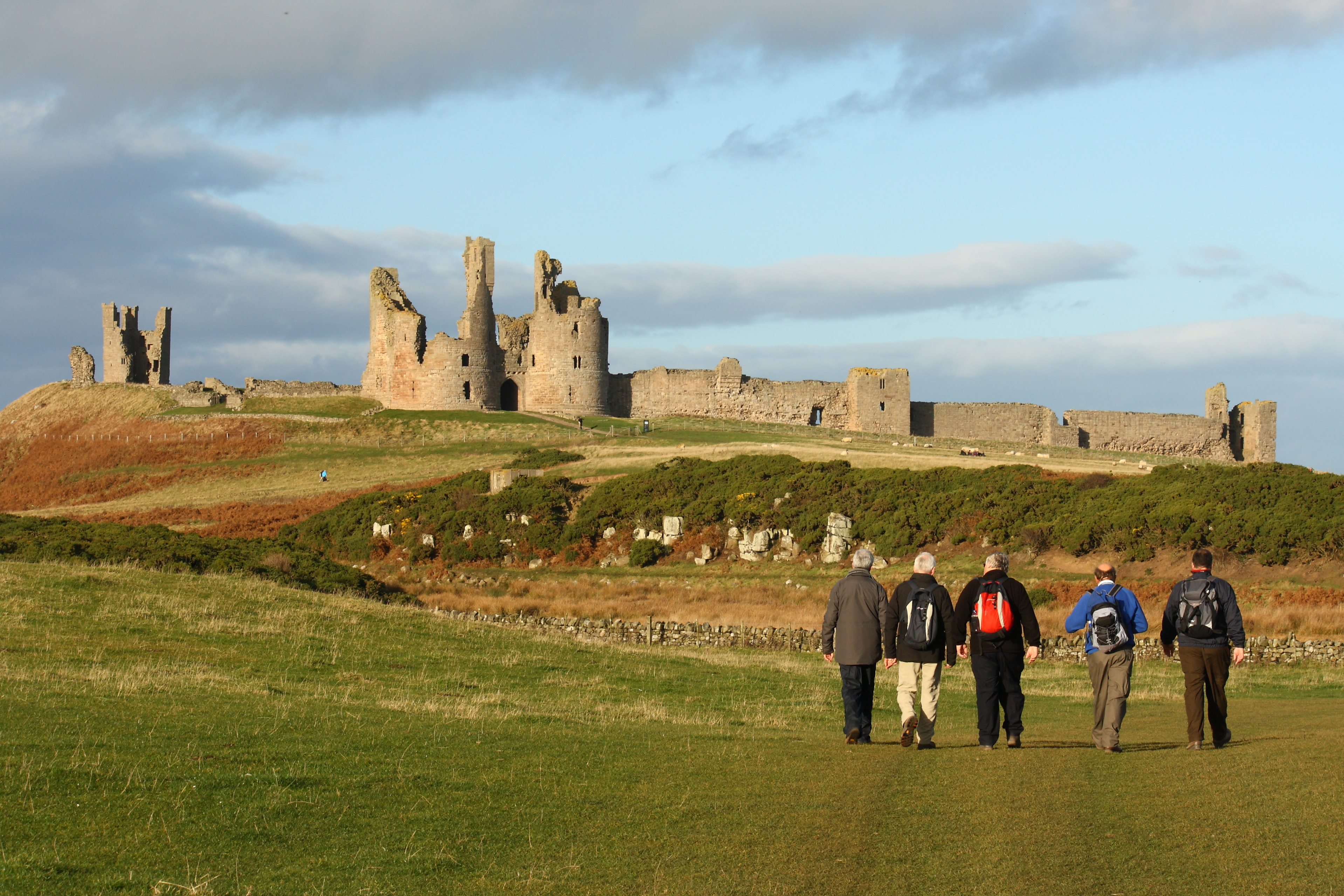 walkers at Dunstanburgh castle in Northumberland, UK